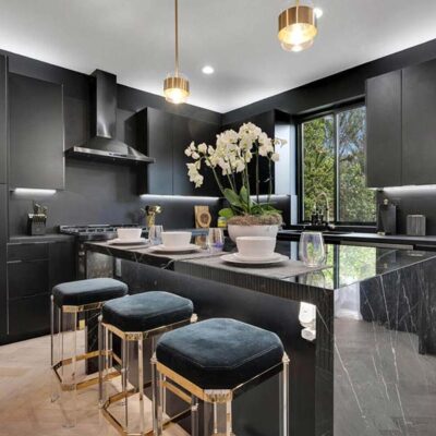 An Industrial-style kitchen with dark cabinets and flowers on the central island