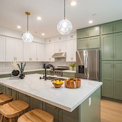 Kitchen with four wooden stools at the island and green cabinets