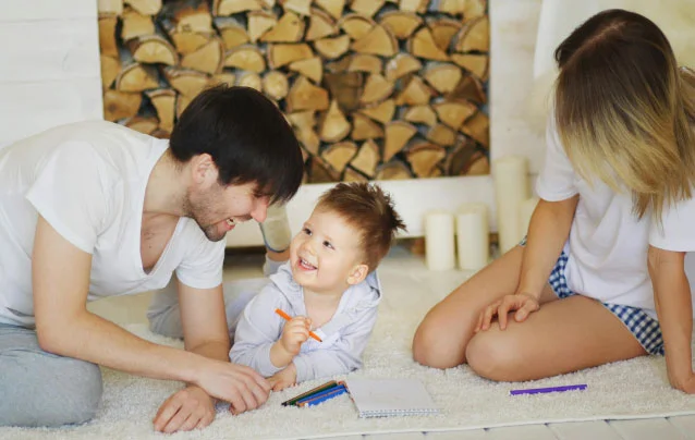 Man, woman, and child laughing on the floor in living space