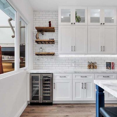 A modern kitchen with white features and an outside view