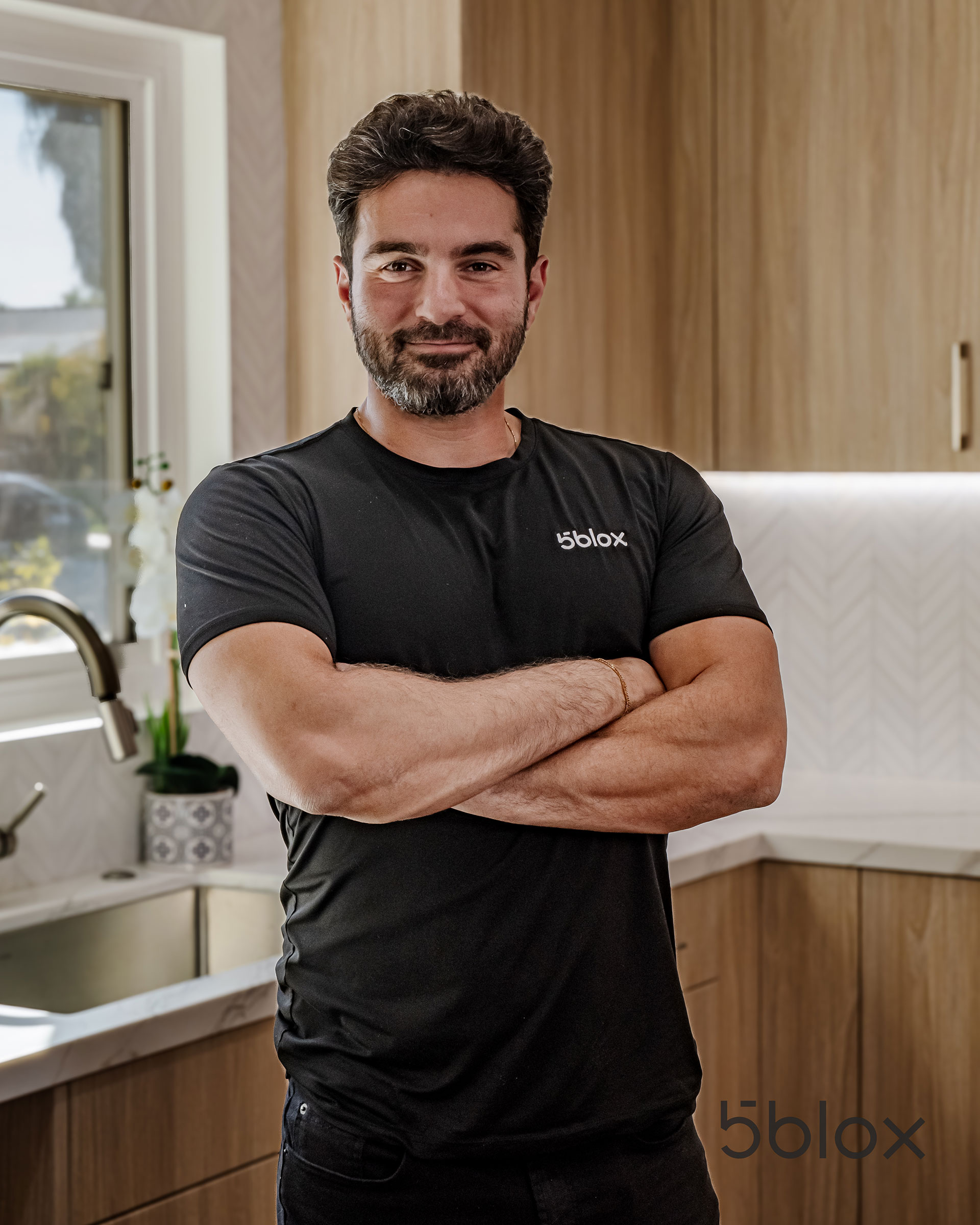 Barak Shemtov, interior design project coordinator, standing in a kitchen with his arms folded