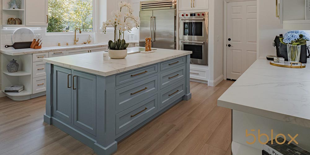 A kitchen with a center island with drawers and light wood flooring