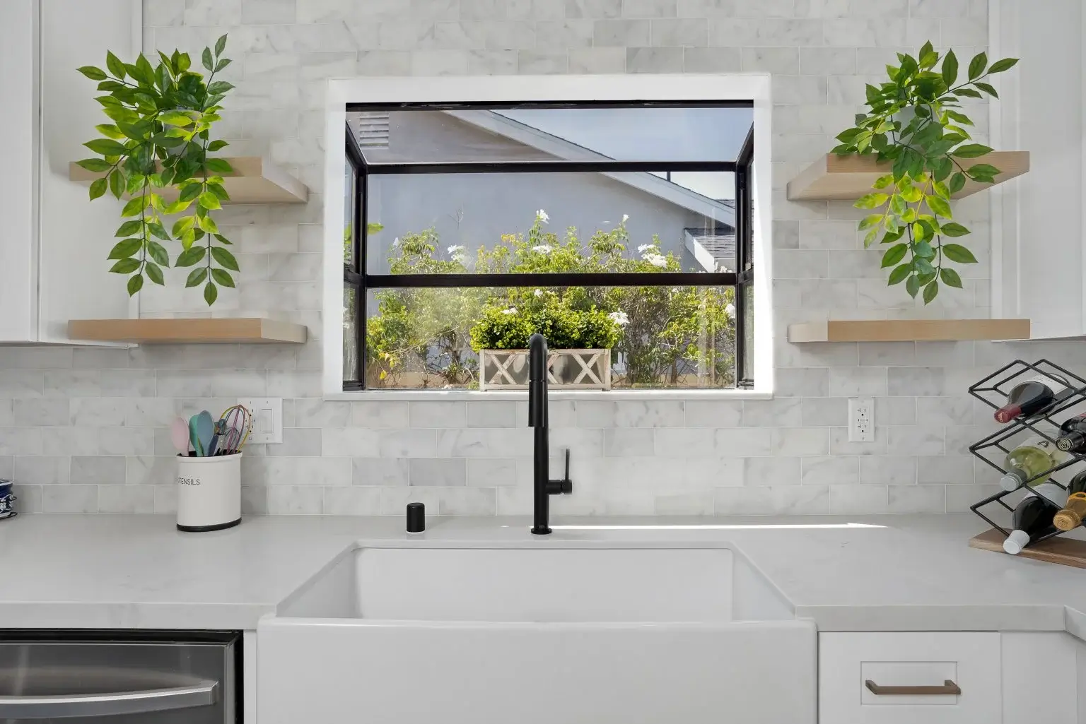 Bright kitchen sink area with black faucet and tile backsplash in Irvine-CA