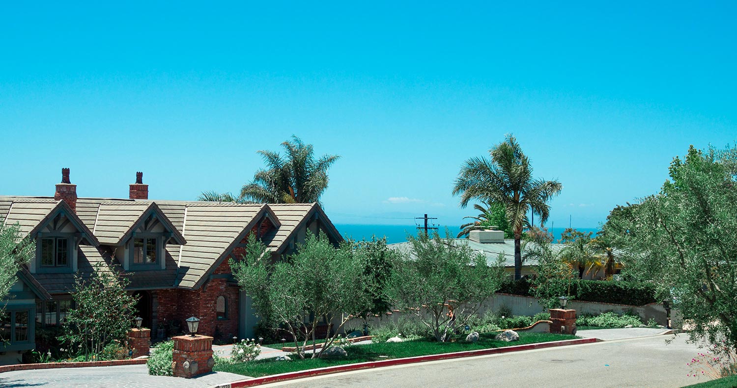 A large house surrounded by palm trees overlooking the ocean