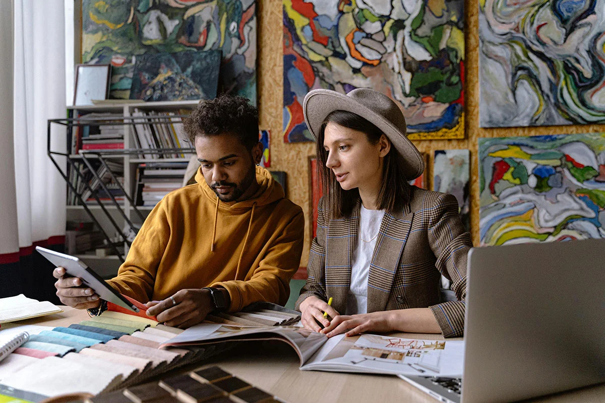 Man and woman sitting at a table looking at design options on tablet