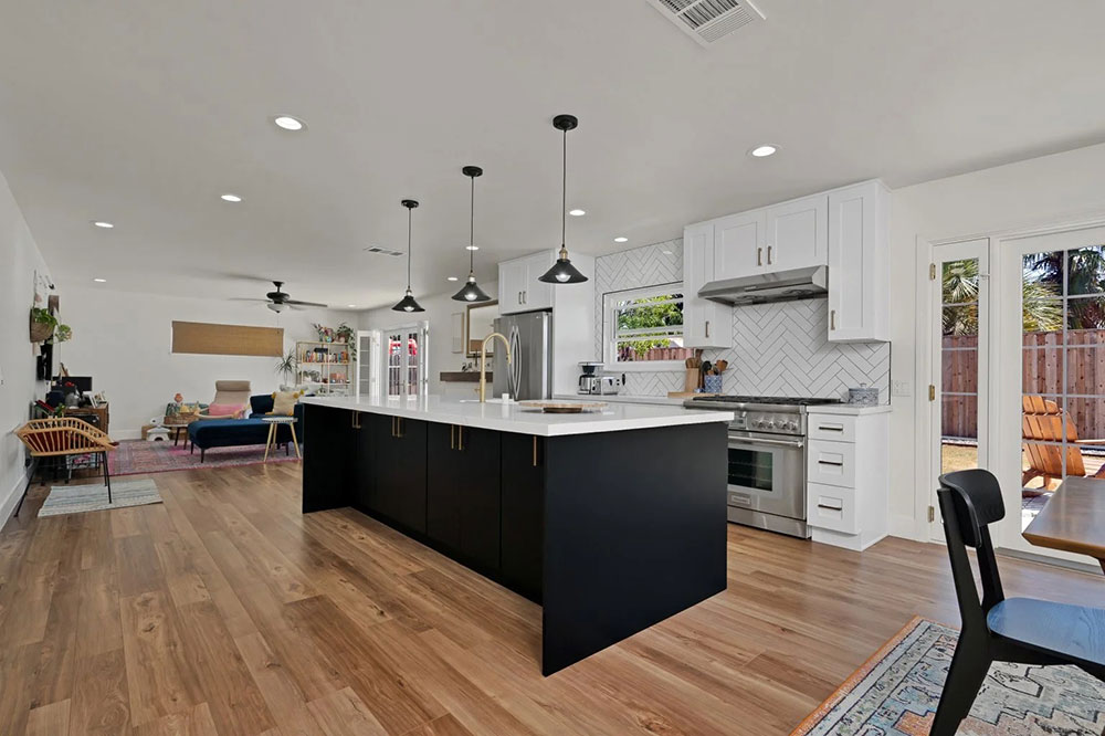 Open-concept kitchen and living space with black island and tile backsplash